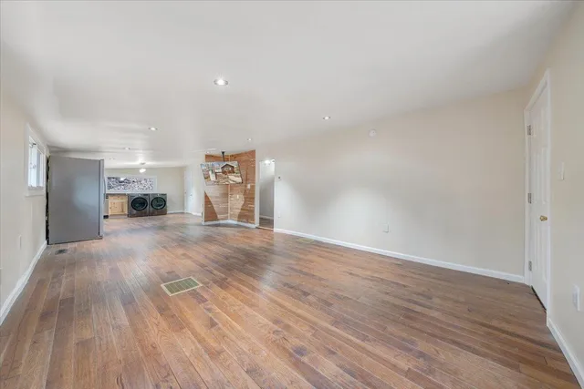 a view of an empty room with a window and wooden floor