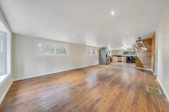 a view of an empty room with wooden floor and a window
