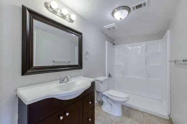 a bathroom with a granite countertop sink mirror vanity bathtub and a toilet