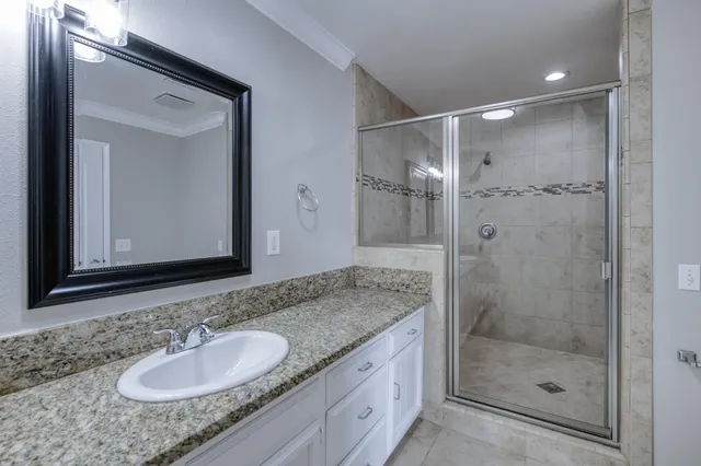 a bathroom with a granite countertop double vanity sink and mirror