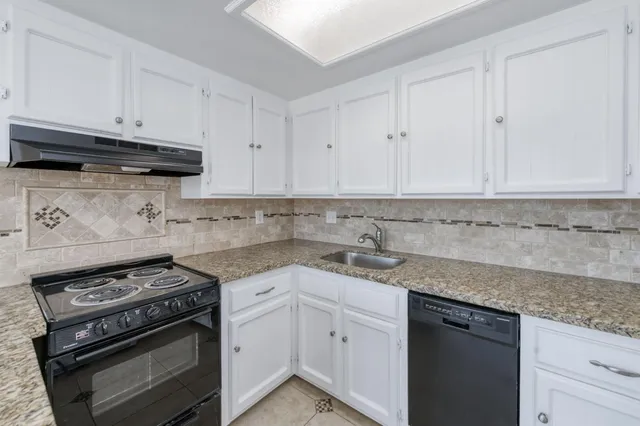 a kitchen with granite countertop white cabinets and stainless steel appliances