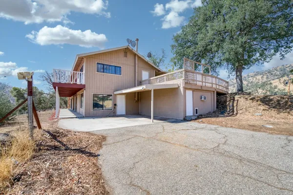a front view of a house with a dirt yard and a large tree