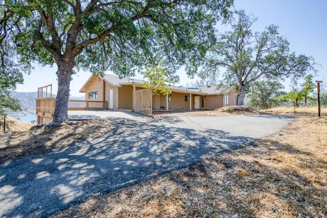 a front view of a house with a dirt yard and a large tree