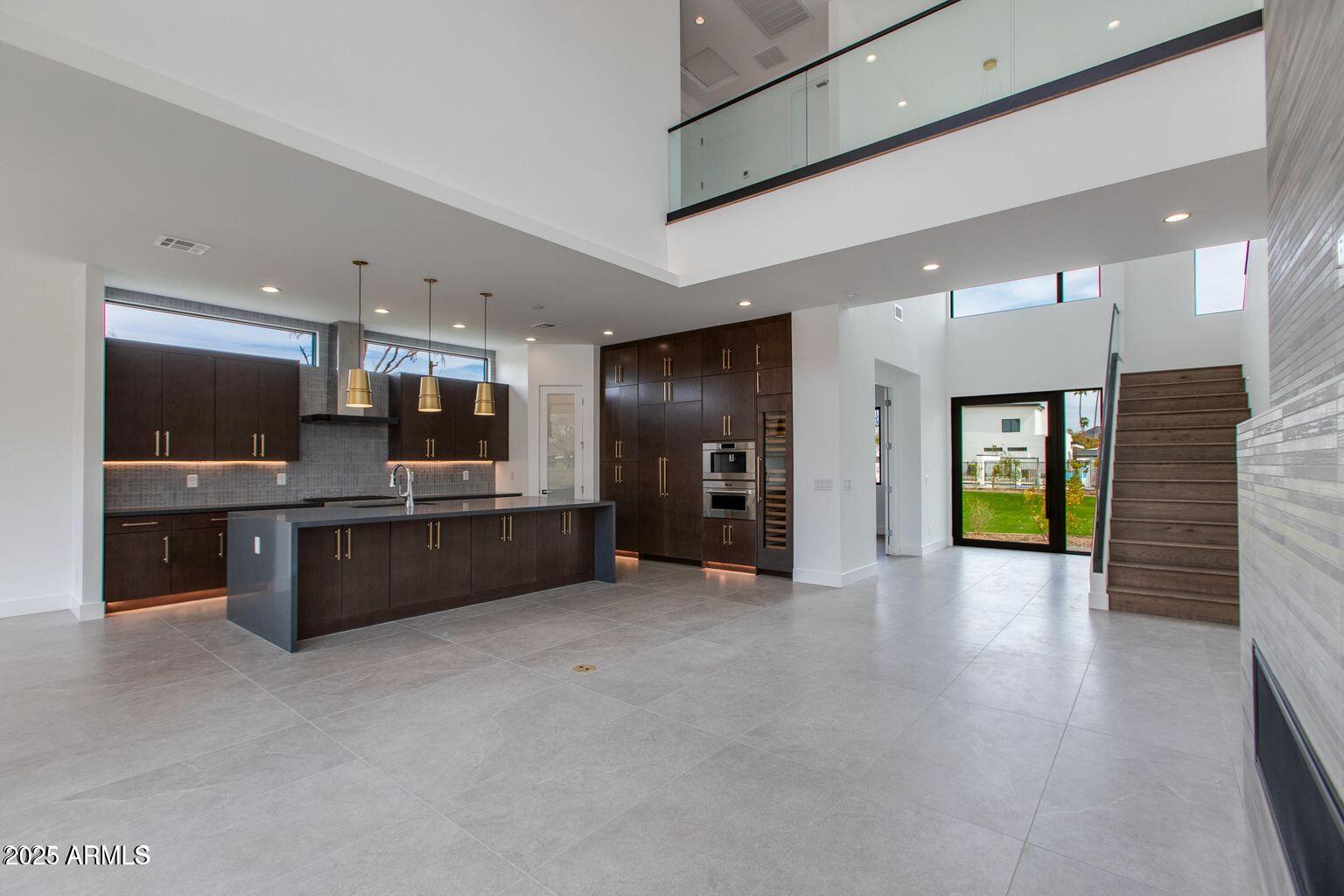 a large living room with stainless steel appliances kitchen island granite countertop a large kitchen view and a fireplace