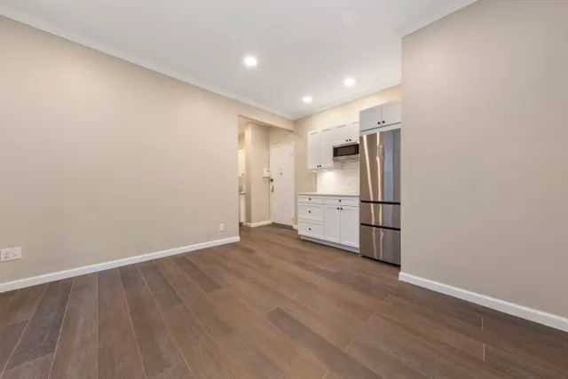 a view of a kitchen with refrigerator and wooden floor