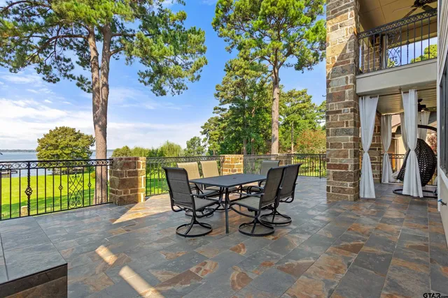 a view of a patio with table and chairs and floor to ceiling window next to a yard