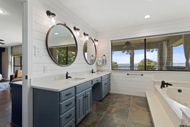 a bathroom with a double vanity sink mirror and a bathtub