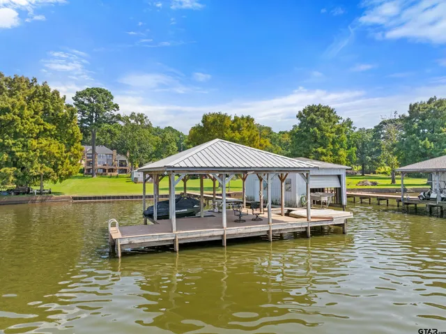 a view of a lake with lawn chairs under an umbrella