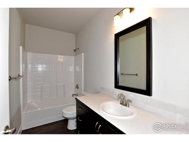 a bathroom with a bathtub shower sink vanity and mirror