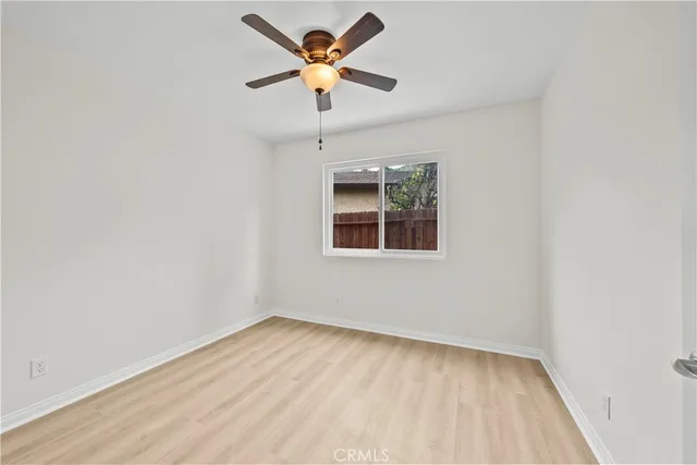an empty room with a window and a fan