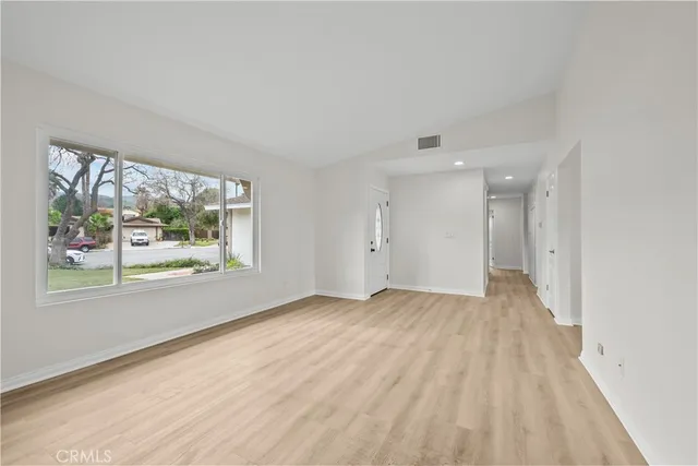 a view of an empty room with a window and wooden floor