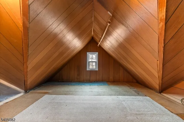 a view of an empty room with wooden walls and stairs