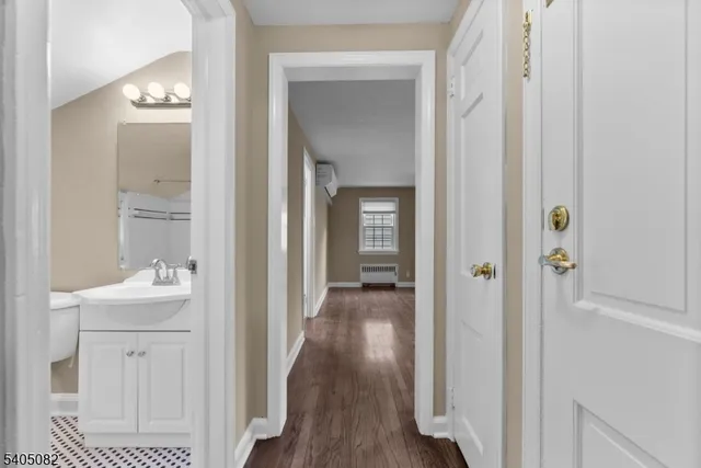 a view of a hallway with wooden floor windows and a bathroom