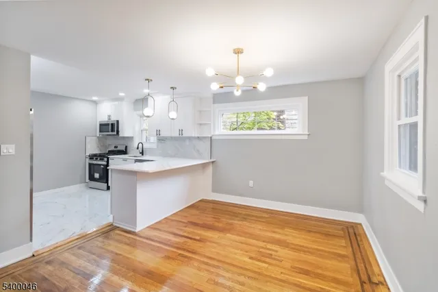 a view of large kitchen with kitchen island stainless steel appliances wooden floor and window
