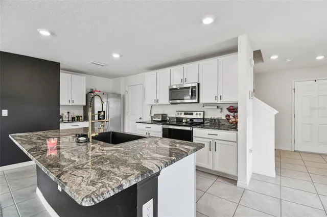 a kitchen with kitchen island granite countertop a sink cabinets and refrigerator