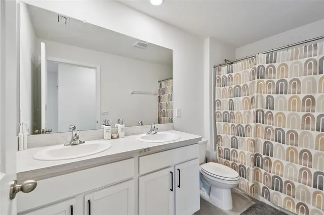 a bathroom with a double vanity sink toilet and shower