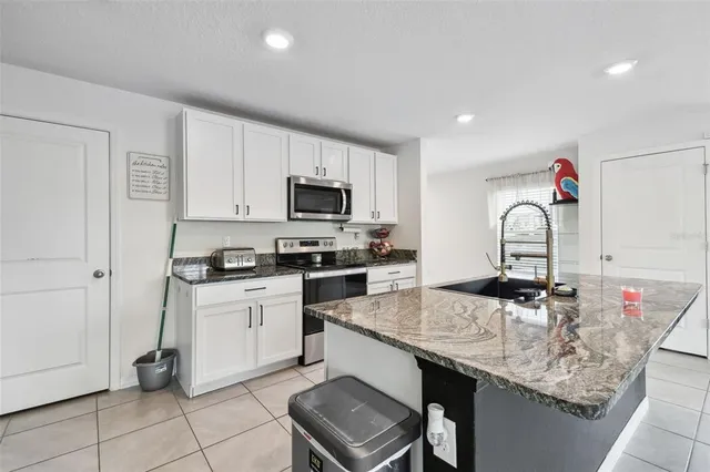 a kitchen with granite countertop a sink stainless steel appliances and white cabinets