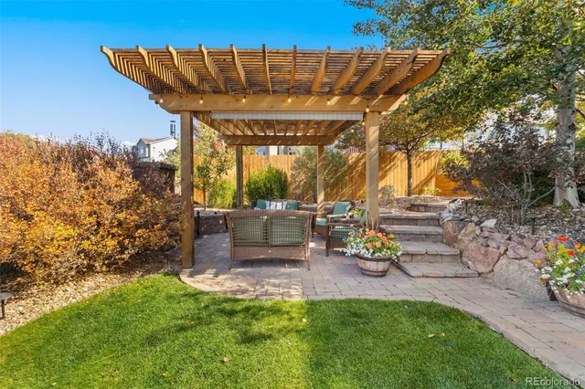 a view of a patio with table and chairs potted plants and a large tree