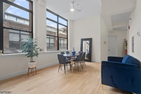a living room with furniture and a dining table with wooden floor