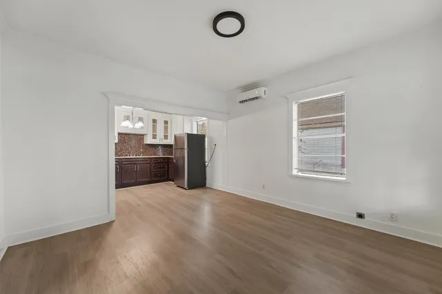 an empty room with wooden floor cabinet and windows