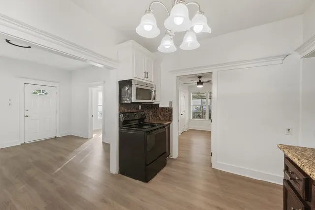 a kitchen with granite countertop a stove cabinets and wooden floor