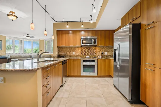 a kitchen with stainless steel appliances granite countertop a refrigerator a stove and a sink with wooden floor