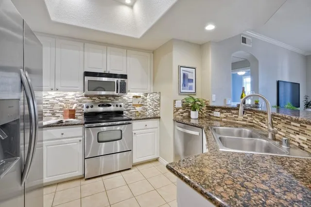 a kitchen with granite countertop a sink stainless steel appliances and cabinets