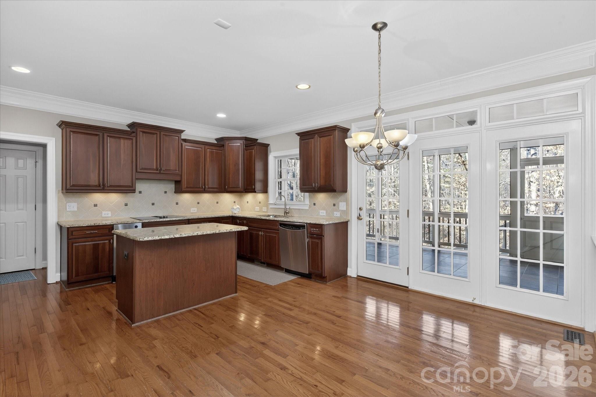 1237 Waynewood Drive Waxhaw, NC 28173 - Photo 9 of 32 a kitchen with kitchen island granite countertop a stove top oven a sink dishwasher a refrigerator and a dining table with wooden floor