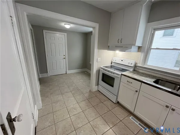 a kitchen with white cabinets a sink and a stove