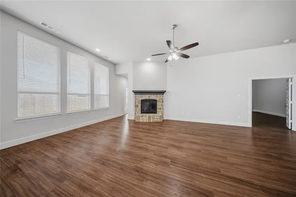 a view of an empty room with wooden floor fireplace and a window