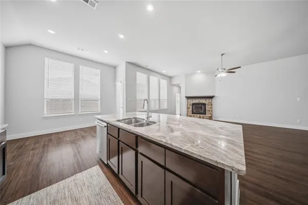 an empty room with wooden floor and a kitchen