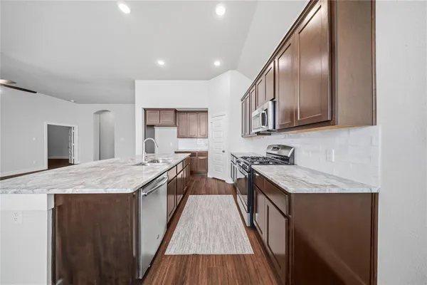 a kitchen with stainless steel appliances granite countertop wooden cabinets a stove top oven a sink and dishwasher