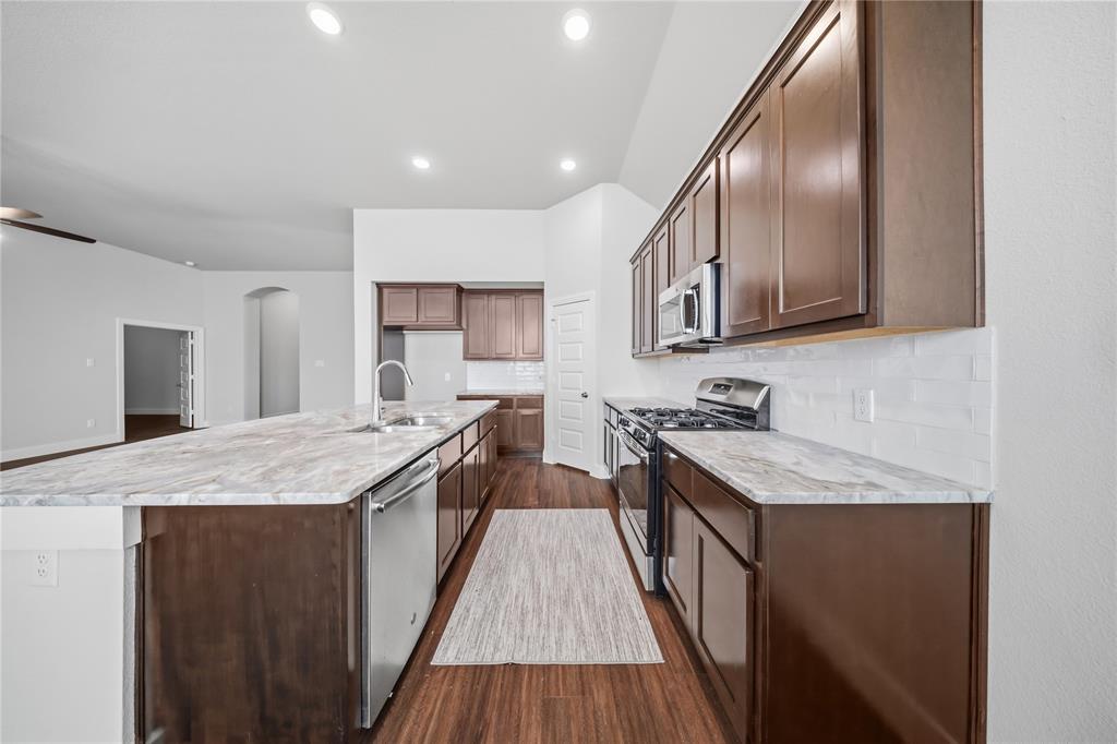1665 Sheldon Drive Forney, TX 75126 - Photo 10 of 35 a kitchen with stainless steel appliances granite countertop wooden cabinets a stove top oven a sink and dishwasher