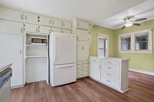 a kitchen with cabinets stainless steel appliances and wooden floor