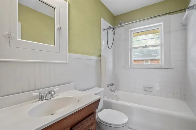 a bathroom with a bathtub shower sink vanity mirror and toilet