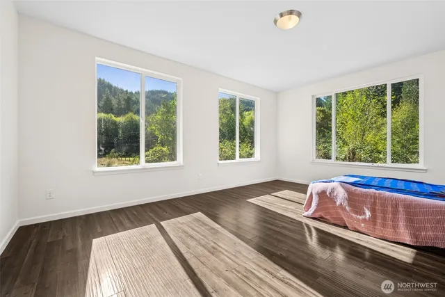 a view of a bedroom with wooden floor and window