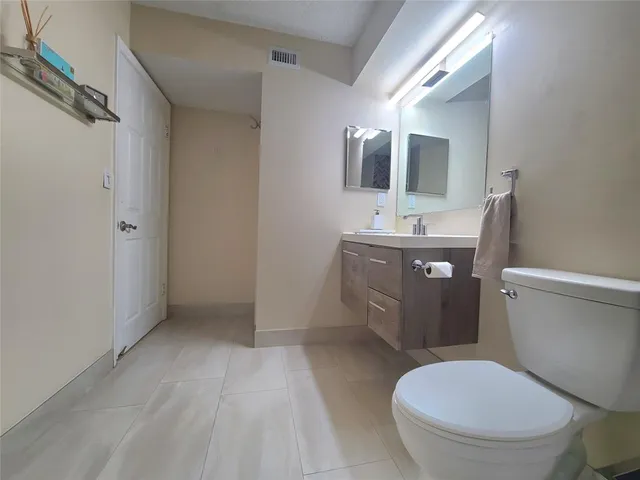 a bathroom with a granite countertop toilet sink and mirror