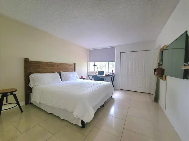 a bedroom with a bed and a refrigerator