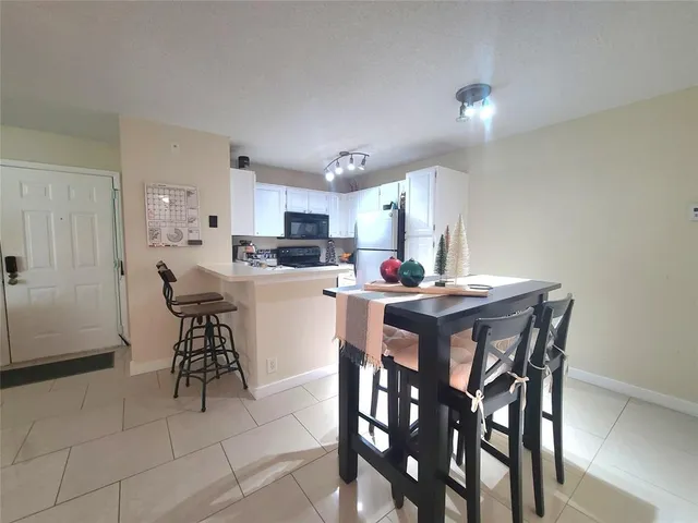 a kitchen with kitchen island a dining table chairs and white cabinets