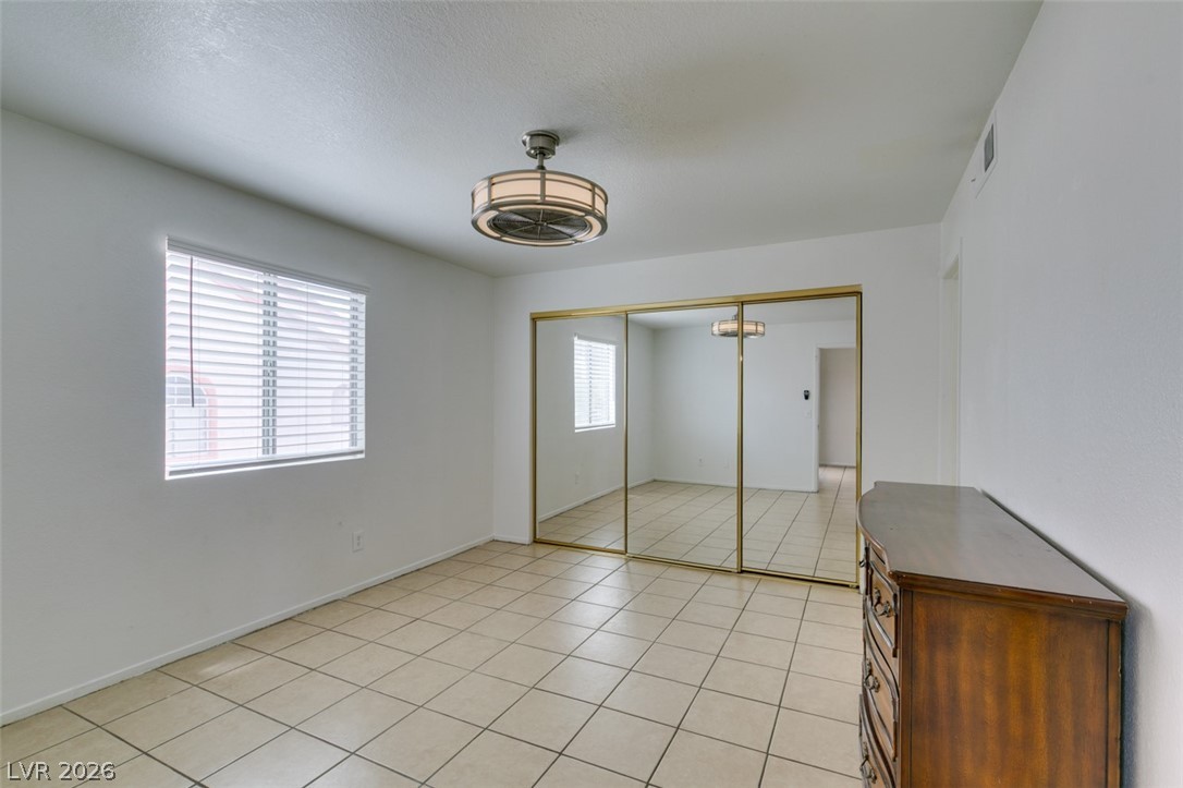 7570 West Flamingo Road, Unit 252 Las Vegas, NV 89147 - Photo 31 of 44 A well-lit bedroom featuring practical mirrored closet doors and durable tile flooring.