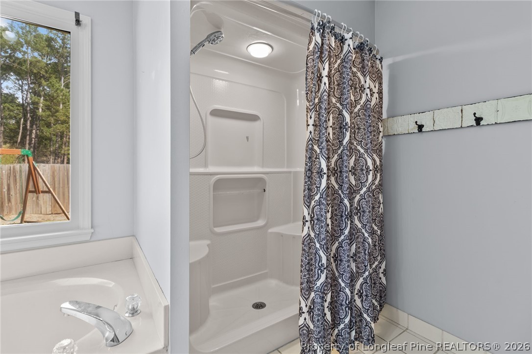 7756 Dragonhead Road Fayetteville, NC 28311 - Photo 21 of 42 a bathroom with a bathtub a shower and a window