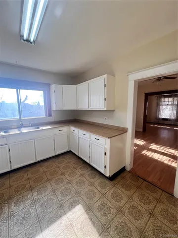 a large kitchen with a stove a sink and dishwasher with white cabinets