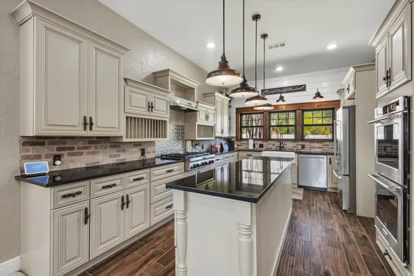 a kitchen with stainless steel appliances granite countertop a sink a stove and a wooden floors