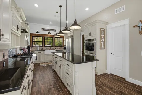 a kitchen with stainless steel appliances kitchen island granite countertop a stove a sink and a refrigerator