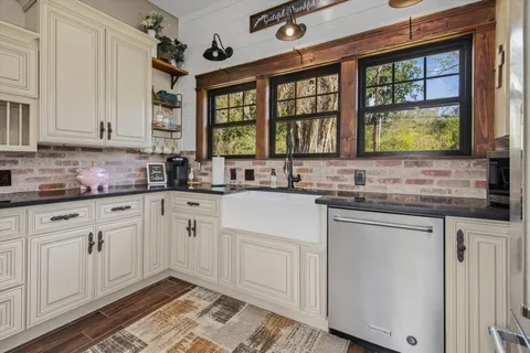 a kitchen with stainless steel appliances granite countertop white cabinets sink and window