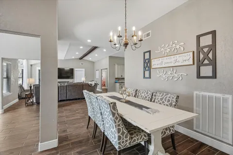 a view of a dining room and livingroom with furniture wooden floor a chandelier
