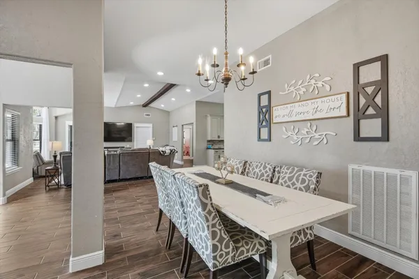 a view of a dining room and livingroom with furniture wooden floor a chandelier