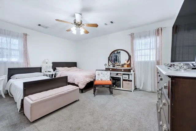 a bedroom with bed and a flat tv screen on dresser
