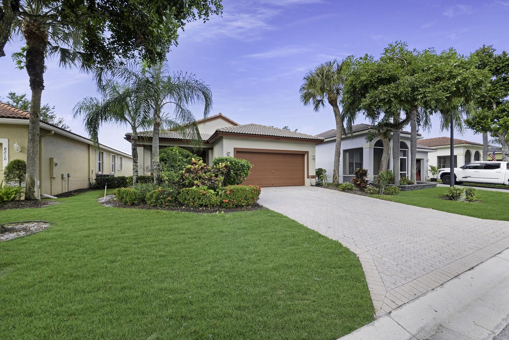 8214 Bellafiore Way Boynton Beach, FL 33472 - Photo 24 of 35 a front view of a house with a garden and palm trees