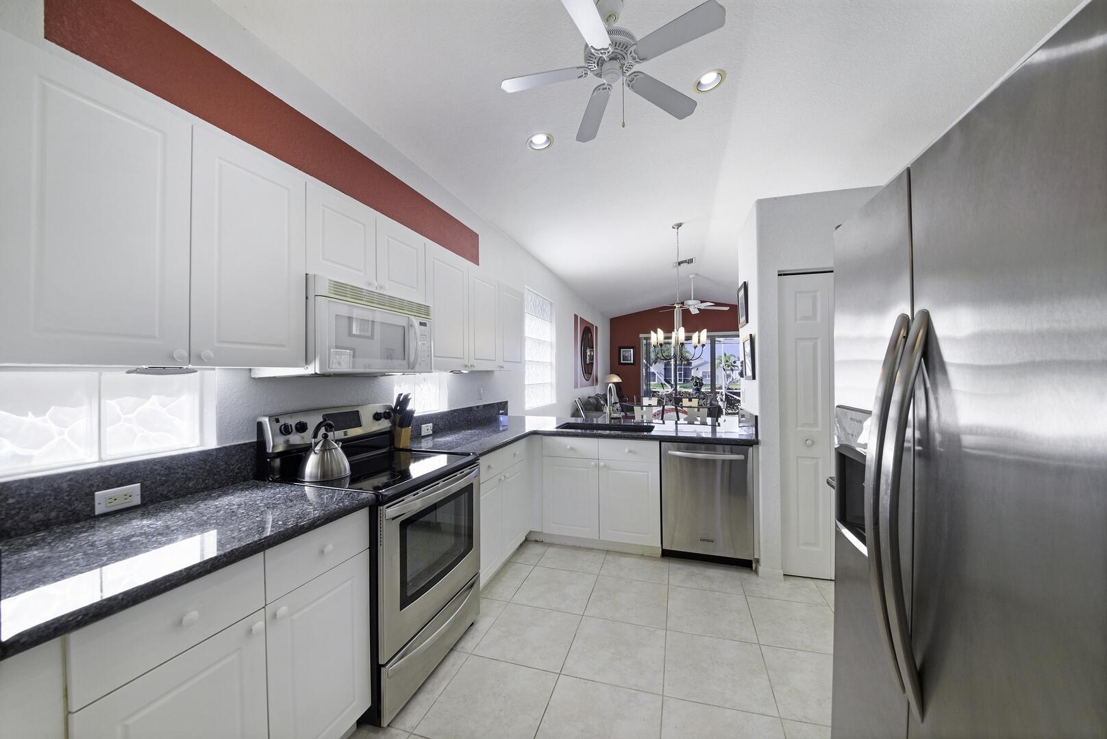 8214 Bellafiore Way Boynton Beach, FL 33472 - Photo 8 of 35 a kitchen with granite countertop stainless steel appliances a sink cabinets and a window
